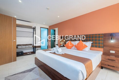 King-size bed with an open clothes rack, storage baskets and in-room safe