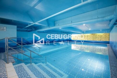Indoor swimming pool with blue mosaic tiles and handrail steps