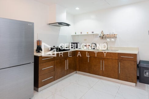 L-shaped kitchen with wood cabinets, induction cooktop, microwave and two-door refrigerator