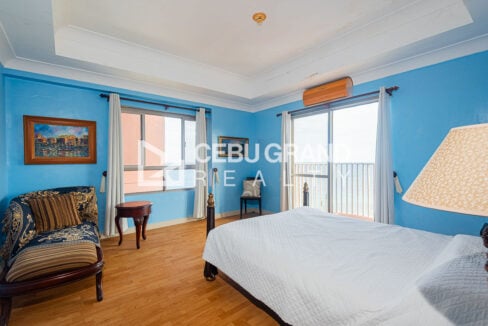 Master bedroom in blue with four-poster bed, chaise lounge and sea-view balcony door