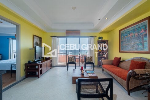 Living room with rattan sofa, wood coffee table and sea view through the balcony doors