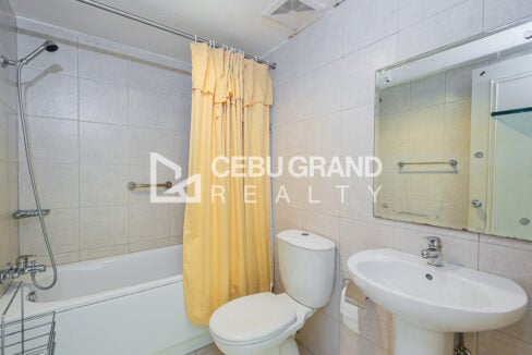 Common bathroom with bathtub, shower curtain, toilet and pedestal sink