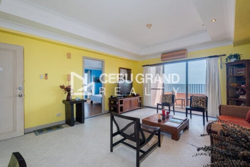 Living area with TV console, split aircon and the balcony overlooking the sea