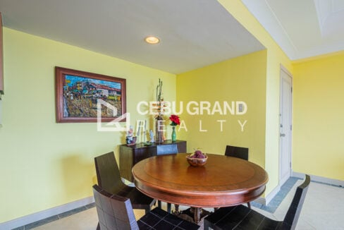 Round wood dining table with dark chairs and a sideboard in the Movenpick condo