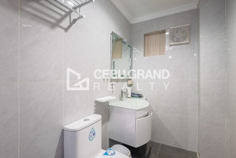 En-suite bathroom with grey tiles, wall-hung basin and toilet
