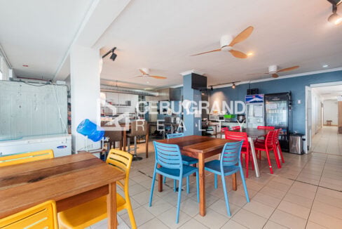 Second-floor dining hall with colorful chairs and ceiling fans at the Mactan dive hotel