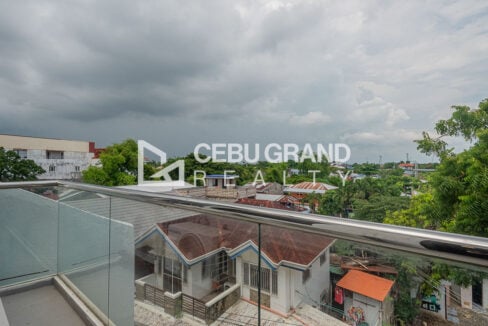 Balcony with a glass railing overlooking the neighborhood greenery
