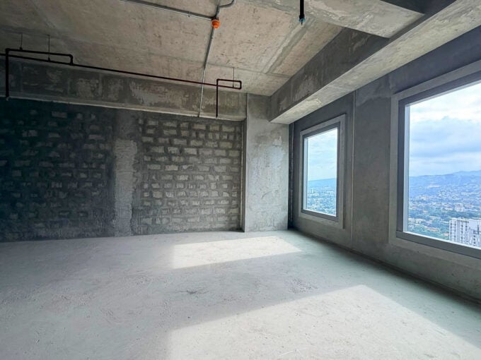Two tall windows framing the hills above Lahug in a bare-shell office unit