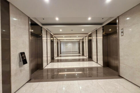 Elevator lobby lined with pale marble and stainless lift doors
