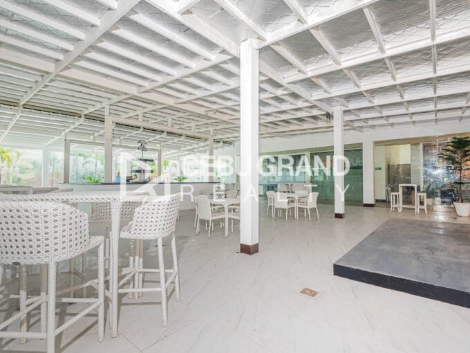 Covered ground-floor dining hall in Kasambagan with white rattan bar seating, a raised platform and a bar counter