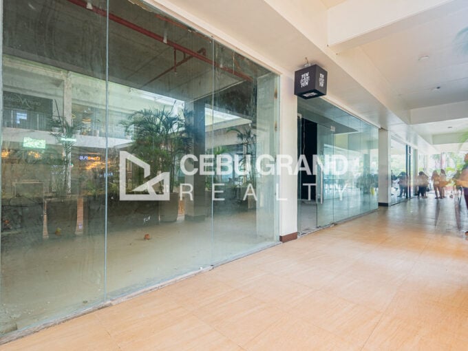 Full-height glass storefront of a ground-floor retail space along a covered arcade in Kasambagan