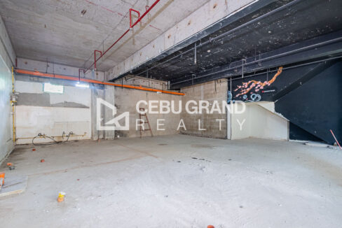 Bare shell retail space with fire sprinkler lines, utility piping and a painted mural wall