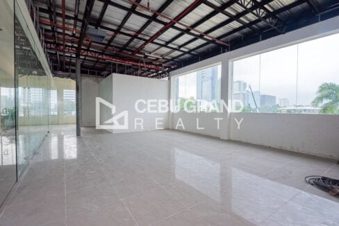 Office floor with wide windows facing city towers and a full-height glass partition wall