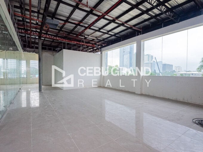 Office floor with wide windows facing city towers and a full-height glass partition wall