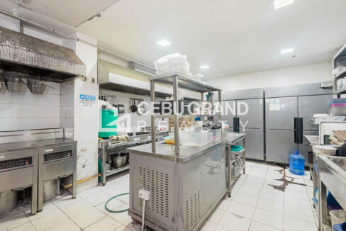 Commercial kitchen with exhaust hoods, fryers, a gas range and upright reach-in chillers