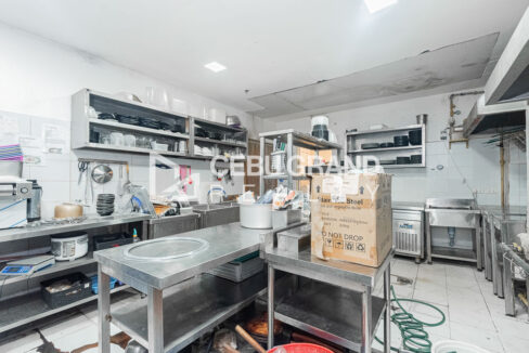 Kitchen prep area with stainless tables, sinks and open steel shelving
