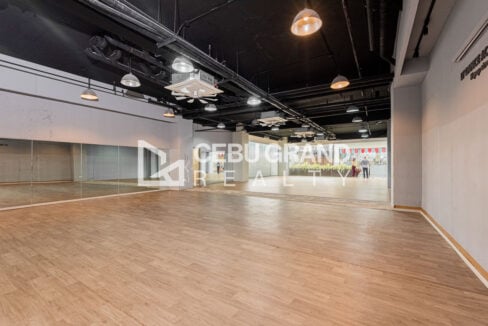 Studio space with mirrors along one wall and a black exposed ceiling