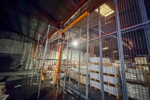 Wire-mesh caged storage enclosure beside the tall concrete wall