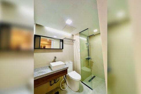 Park Tower bathroom with a vessel sink, black-framed mirror and frameless glass shower