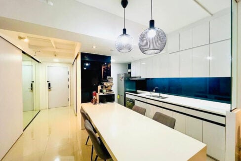 White gloss kitchen with a dark blue glass backsplash and a long dining island