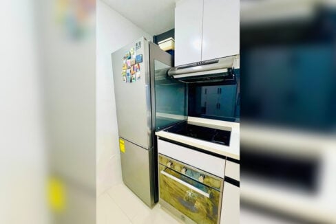 Two-door refrigerator beside the cooktop, range hood and built-in oven