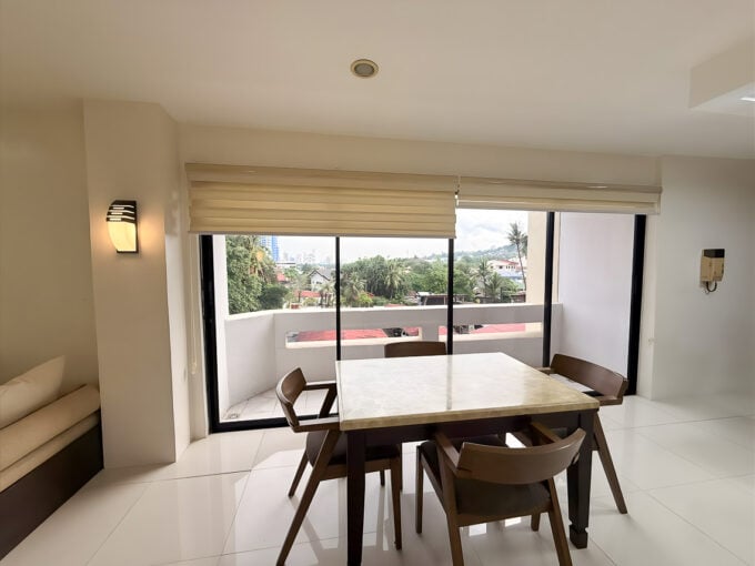 Dining area with floor-to-ceiling glass doors to a balcony overlooking trees and the hills