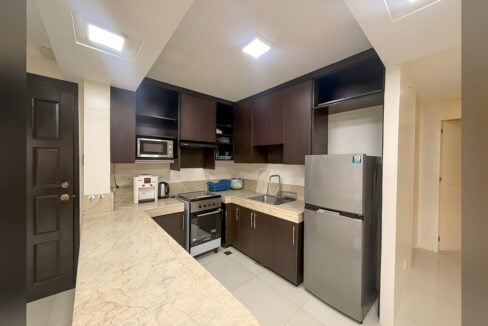 Kitchen with dark wood cabinets, marble-look counters, electric range with oven and two-door refrigerator