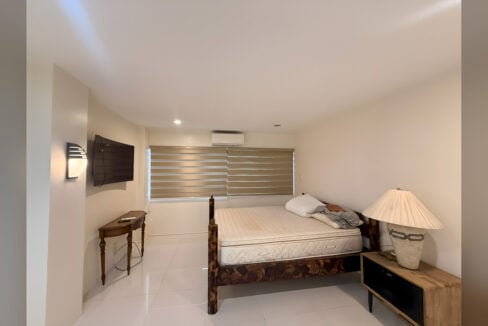 Bedroom with wood-frame bed, wall-mounted TV, split aircon and zebra blinds