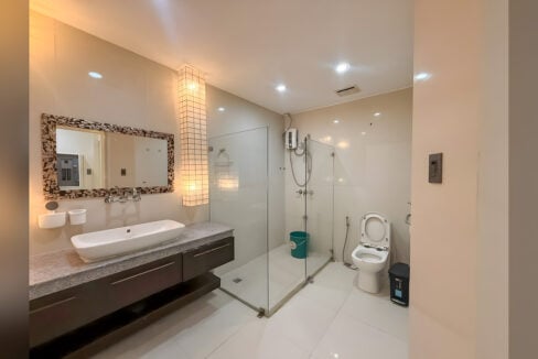 Bathroom with vessel sink, mosaic-framed mirror, glass shower with water heater and toilet