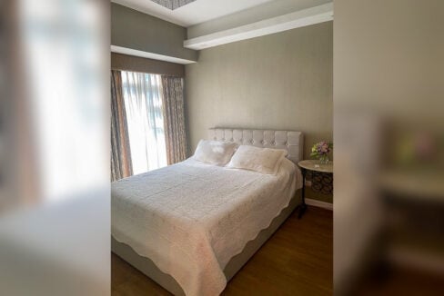 Bedroom with tufted headboard in a furnished 1BR condo for rent at Solinea