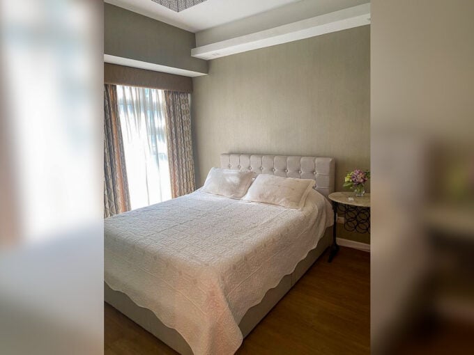 Bedroom with tufted headboard in a furnished 1BR condo for rent at Solinea
