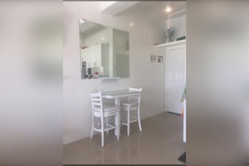 Bar-height table for two with white stools and a wall mirror near the entry door