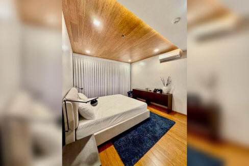 Master bedroom with upholstered bed, console and split-type aircon in a 2BR corner condo for rent at The Reef, Mactan