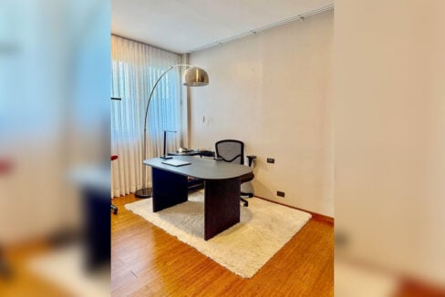 Second bedroom set up as a study with desk and arc floor lamp in a 2BR corner condo for rent at The Reef, Mactan