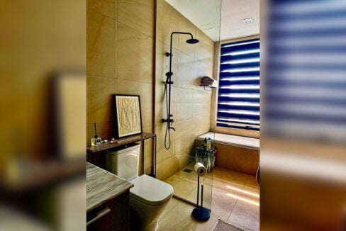 Glass-partitioned rain shower and bathtub under the window in a 2BR corner condo for rent at The Reef, Mactan