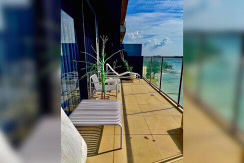 Sea-view terrace with glass railing and slatted lounge chairs in a 2BR corner condo for rent at The Reef, Mactan