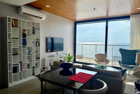 Dining table, white bookshelf and floor-to-ceiling glass with sea view in a 2BR corner condo for rent at The Reef, Mactan