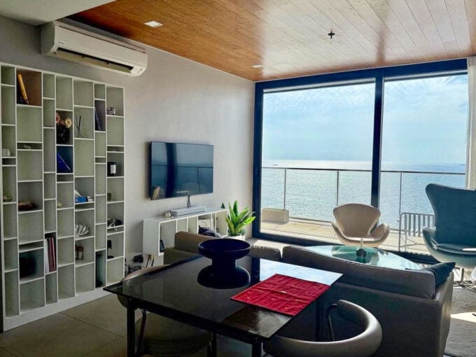 Dining table, white bookshelf and floor-to-ceiling glass with sea view in a 2BR corner condo for rent at The Reef, Mactan