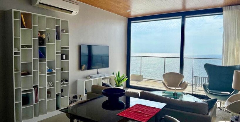 Dining table, white bookshelf and floor-to-ceiling glass with sea view in a 2BR corner condo for rent at The Reef, Mactan