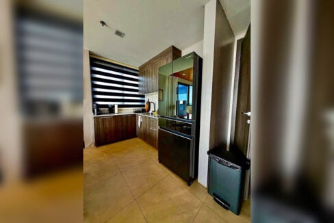 Kitchen with Panasonic French-door refrigerator and wood-grain cabinets in a 2BR corner condo for rent at The Reef, Mactan