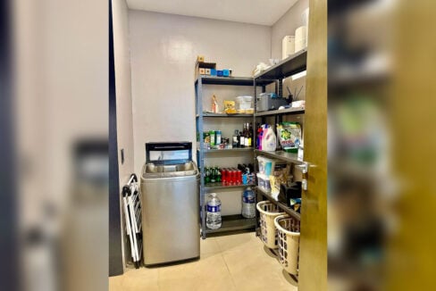 Laundry and storage room with washing machine and shelving in a 2BR corner condo for rent at The Reef, Mactan