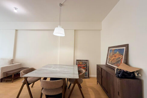 Marble-look dining table with upholstered chairs beside a walnut sideboard