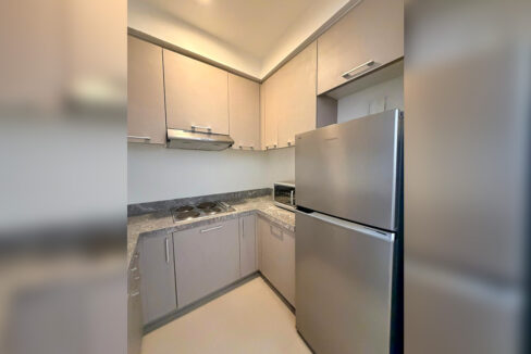 Kitchen with grey cabinets, electric cooktop, range hood and a stainless two-door refrigerator