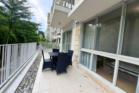 Garden terrace with a rattan-style dining set outside the Raffia building at 32 Sanson