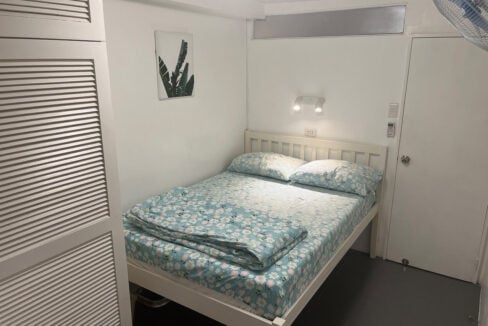 Bedroom with a white double bed beside a louvered wardrobe