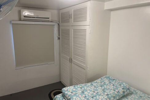 Split-type aircon above a roller blind next to the built-in wardrobe