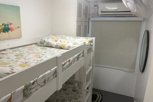 Bunk bed facing the window, aircon and round wall mirror