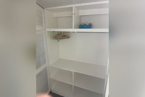 Inside a custom closet with hanging rail and open shelves