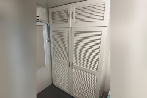 Custom louvered wardrobe with overhead cabinets