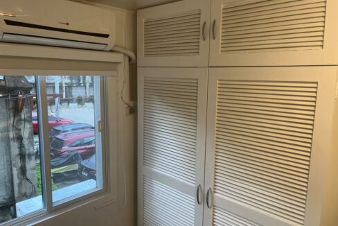 Louvered wardrobe beside a sliding window and split-type aircon